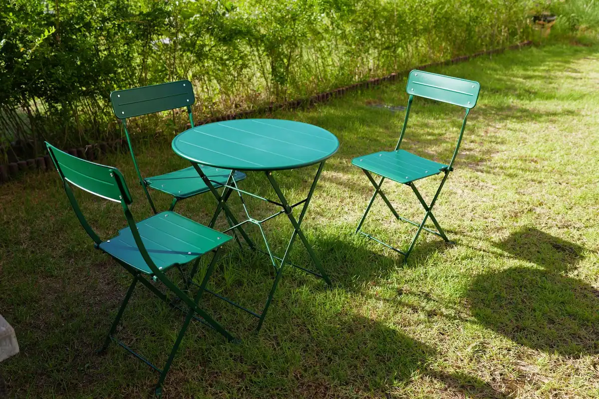 Chaises et table pliantes rangées contre un mur dans un petit jardin