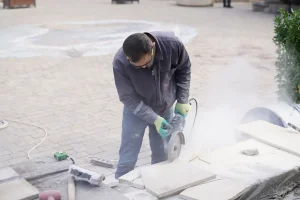 Mains d'un paysagiste posant des pavés de pierre naturelle sur une allée de jardin