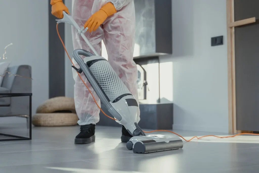 Mains nettoyant un tapis avec une brosse douce, poussière visible et produits de nettoyage à proximité