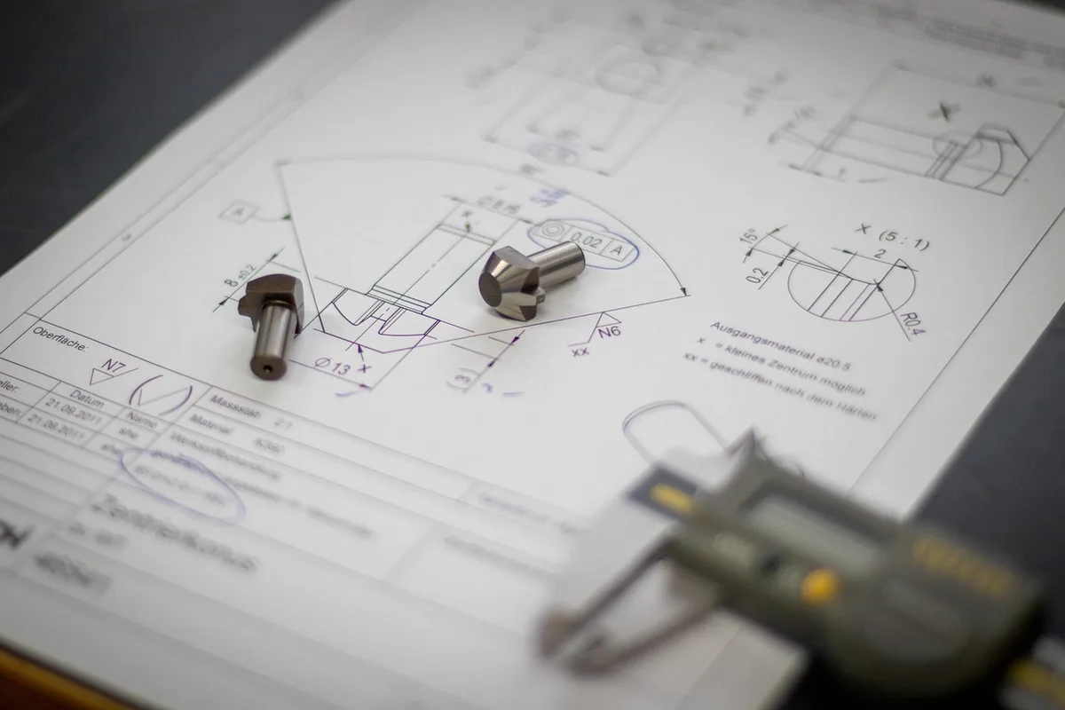 Dossier technique et plans posés sur une table d'atelier en plein jour